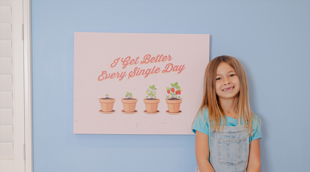 little girl smiling in front of a children's canvas art on a blue wall.